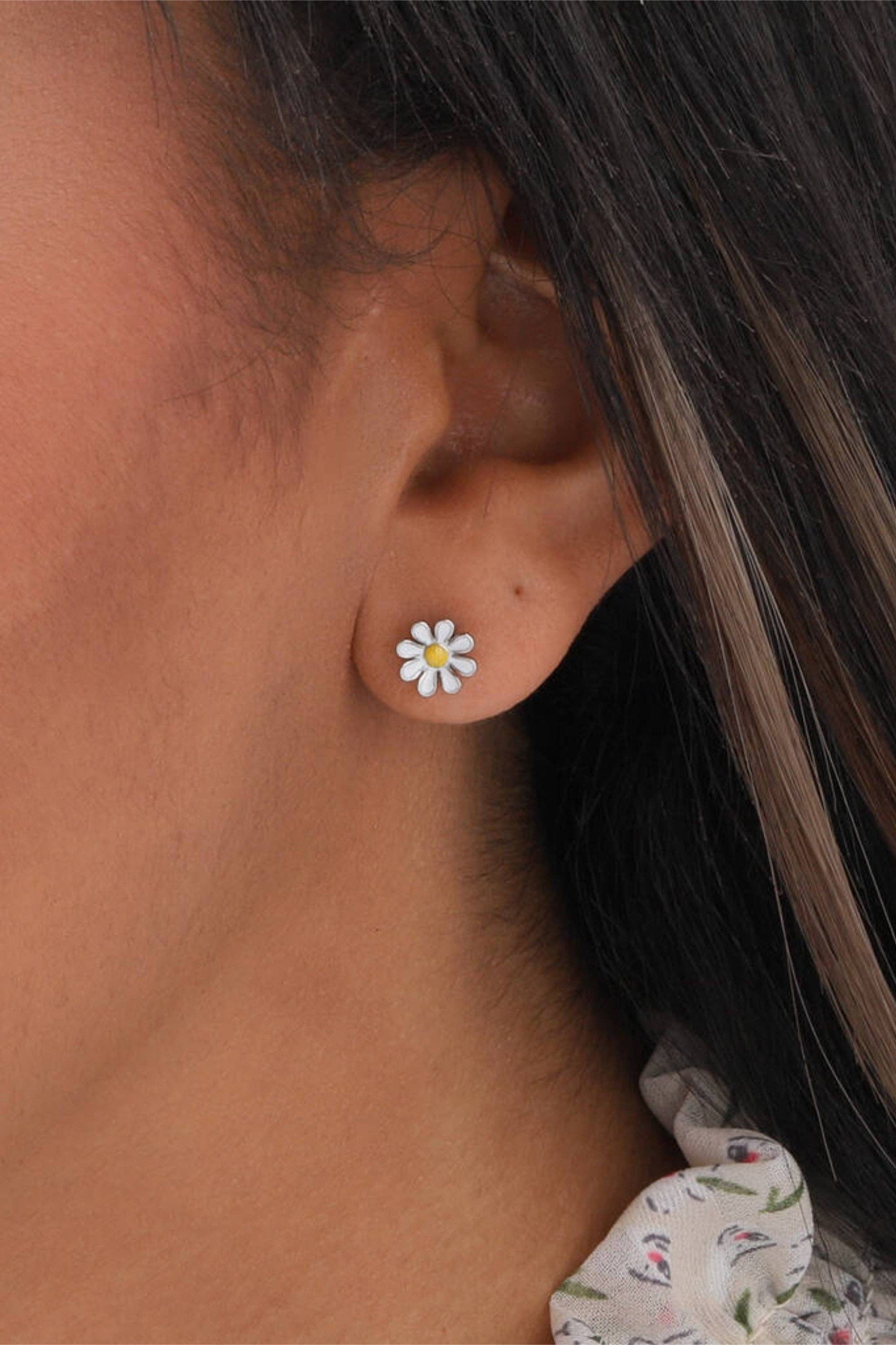 Close-up of a person wearing a floral stud earring.